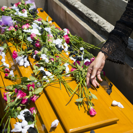 Sarg mit Blumen und einer berührenden Hand